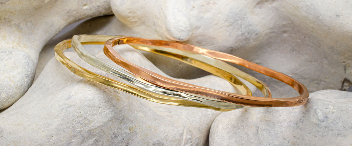 Three solid bangles on a rocky background