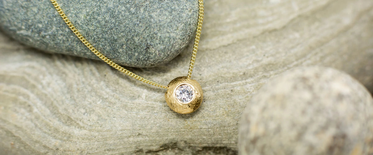 Gold and diamond nugget pendant on rock background