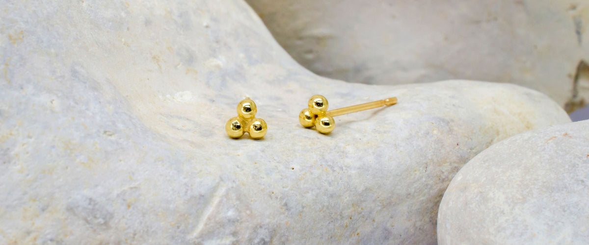 Small charm ear studs on rock background