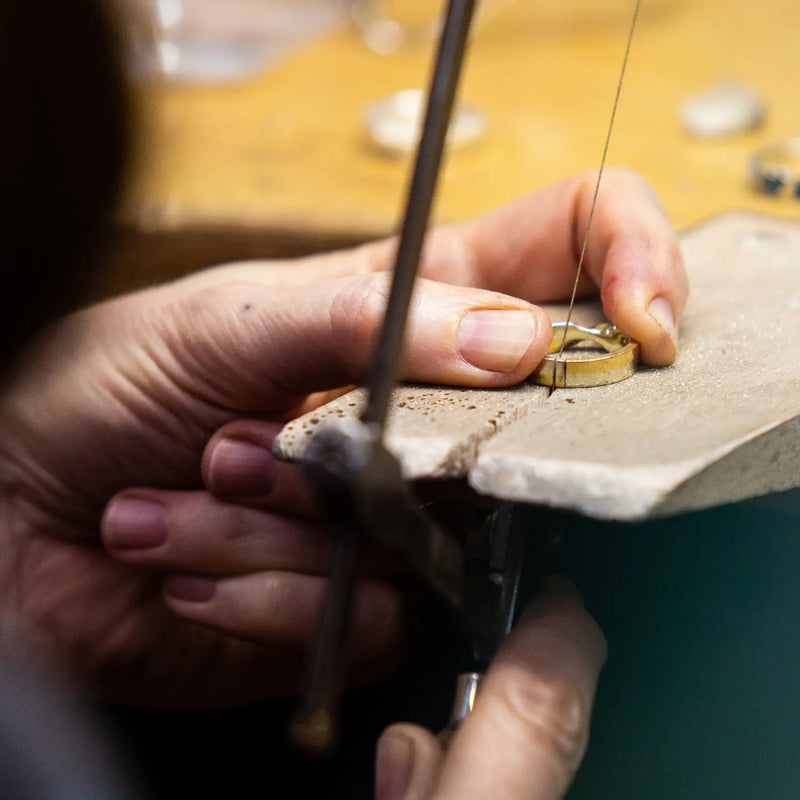 At a jewellers bench sawing into a ring