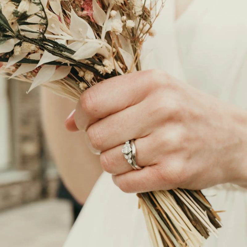 Hand with engagement rings and wedding ring holding flowers