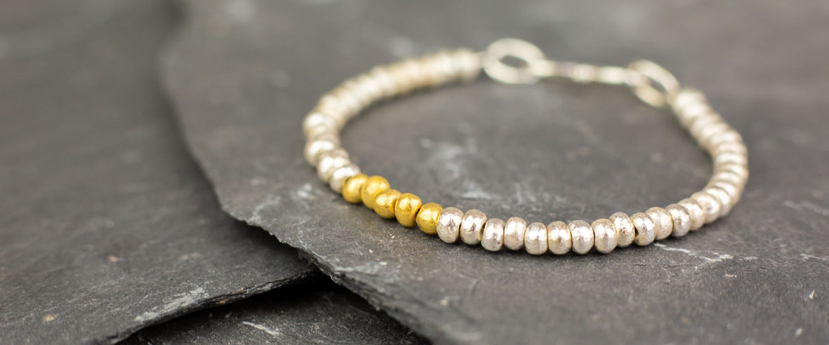 silver and gold nugget bracelet on rock background