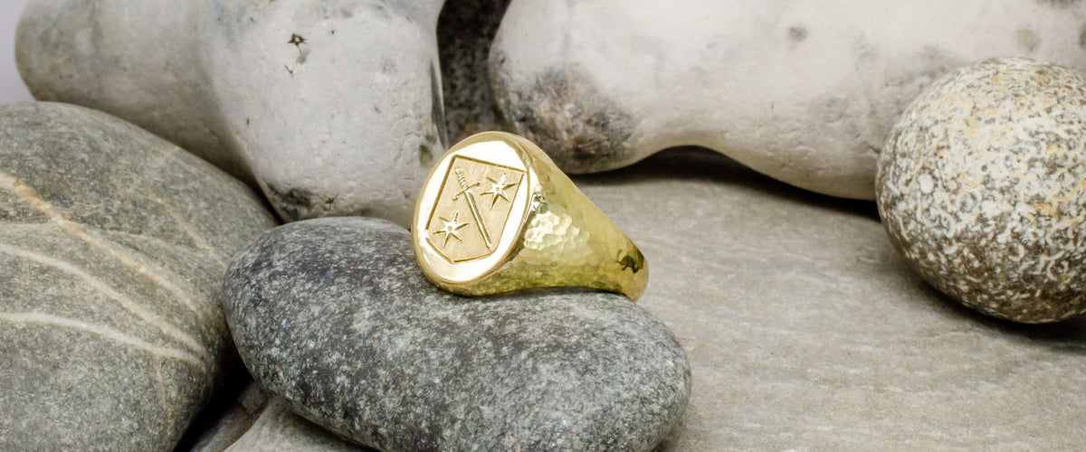 Gold custom signet ring on rock background.