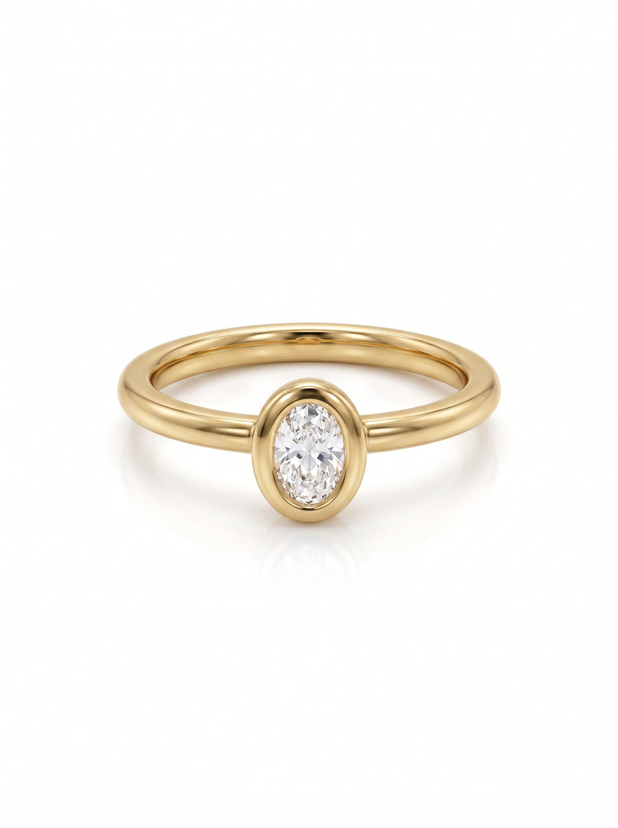 Oval cut diamond engagement ring in a yellow gold bezel setting on a white background.