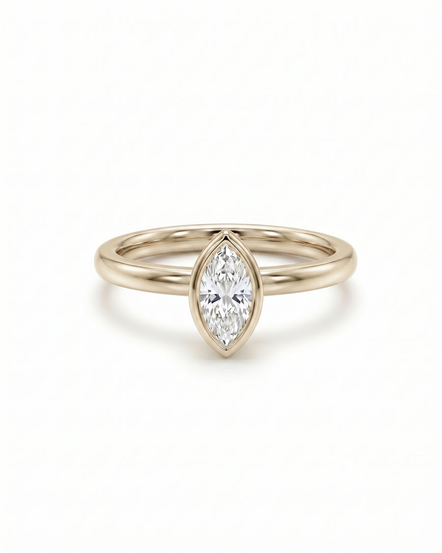 Marquise cut diamond engagement ring in a yellow gold bezel setting on a white background.