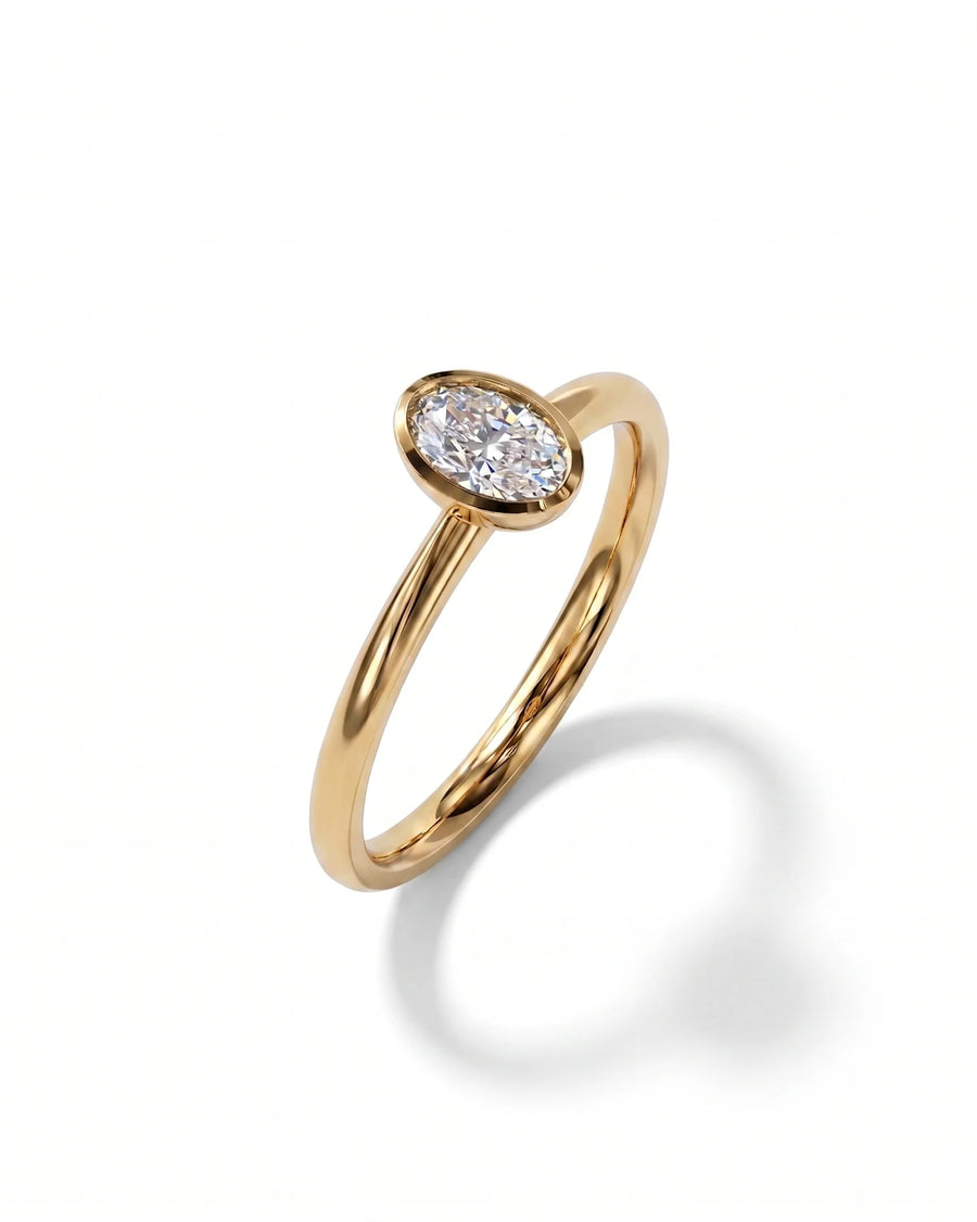 Gold engagement ring with an oval cut natural diamond in a bezel setting.