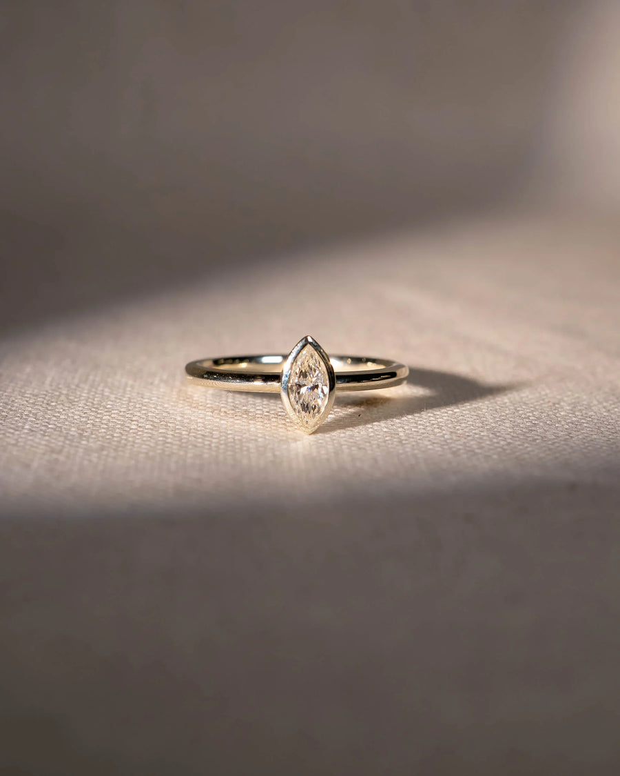 Gold ring with a marquise cut natural diamond in a bezel setting.