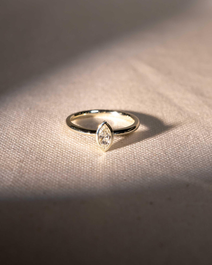 Yellow gold ring with a marquise cut natural diamond in a bezel setting.
