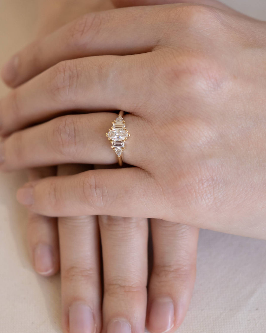 Gold engagement ring with marquise and baguette cut diamonds on a hand.