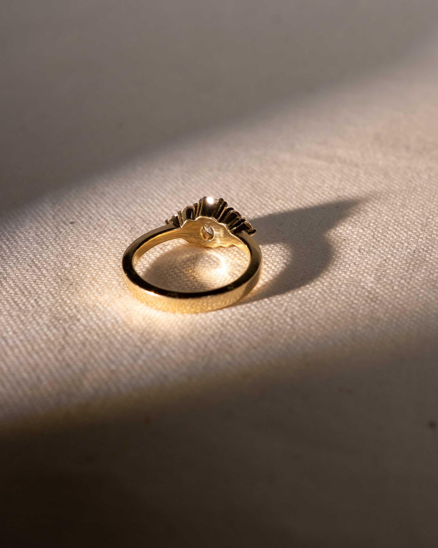 Gold ring with organic, textured design on fabric in natural sunlight, handmade luxury jewelry