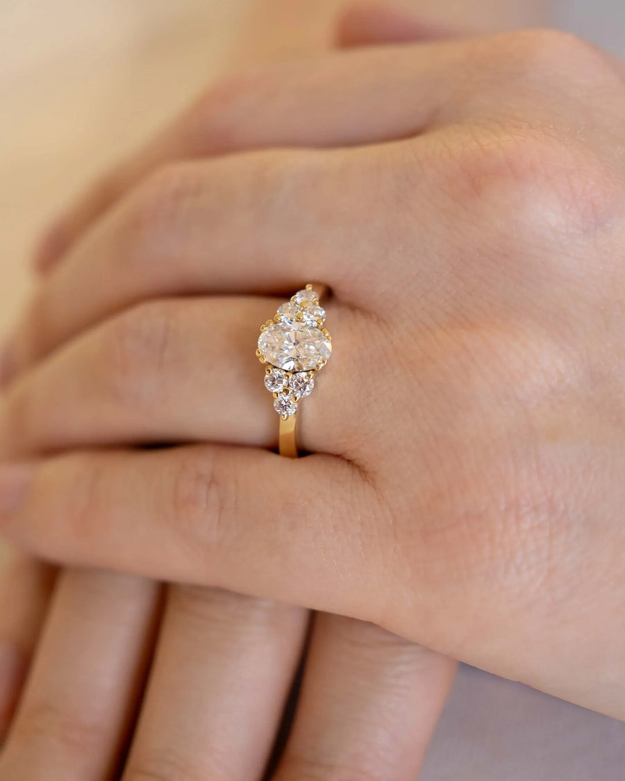 Hand wearing a unique gold diamond engagement ring with organic cluster design