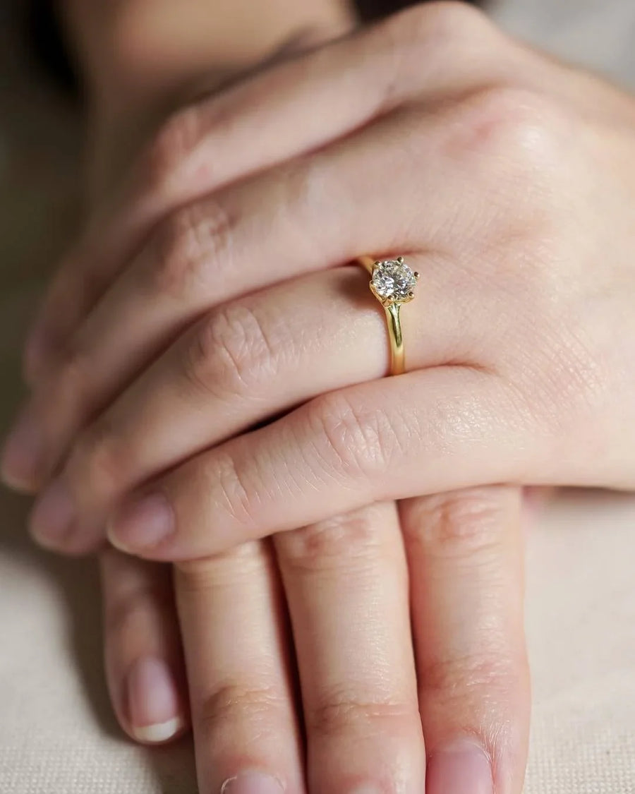 Gold tulip solitaire engagement ring with round diamond on hand