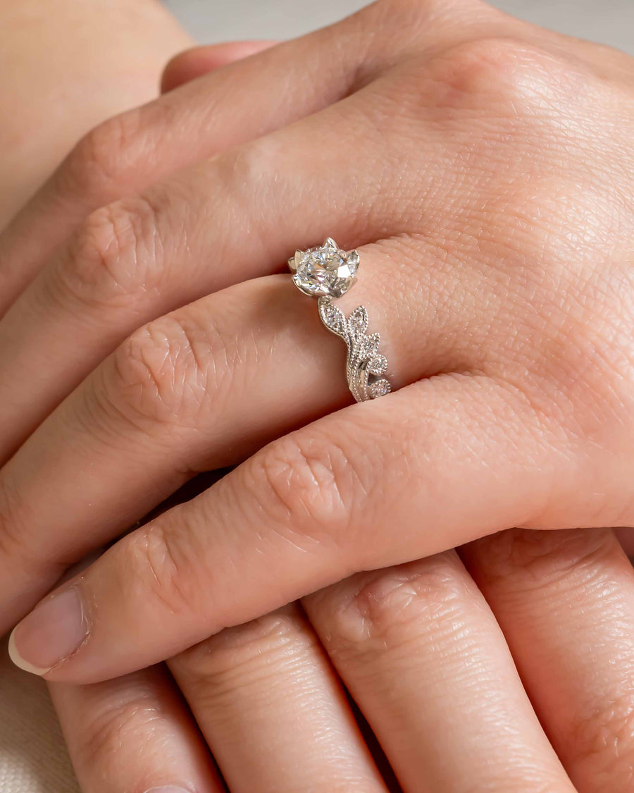 Silver ring with a round diamond and beaded, leaf-like band.