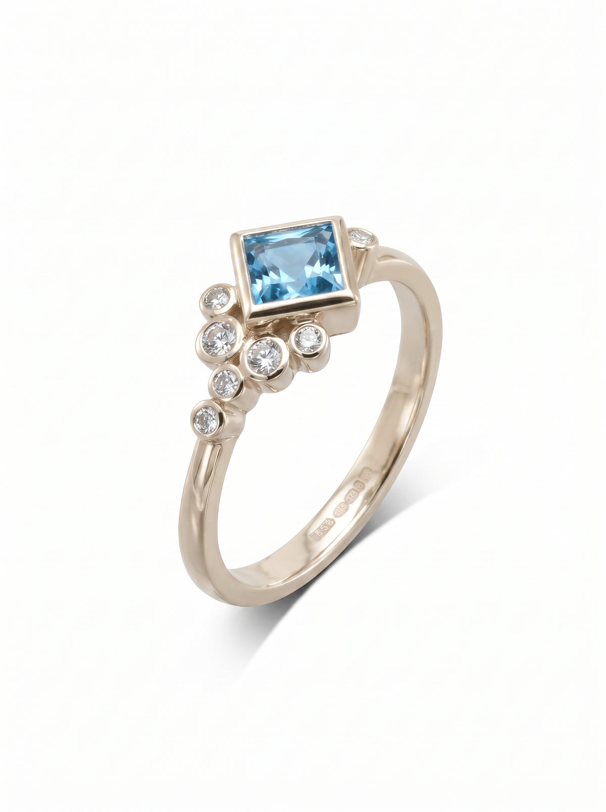 Rose gold engagement ring featuring a square blue topaz accented by a cluster of small round diamonds.