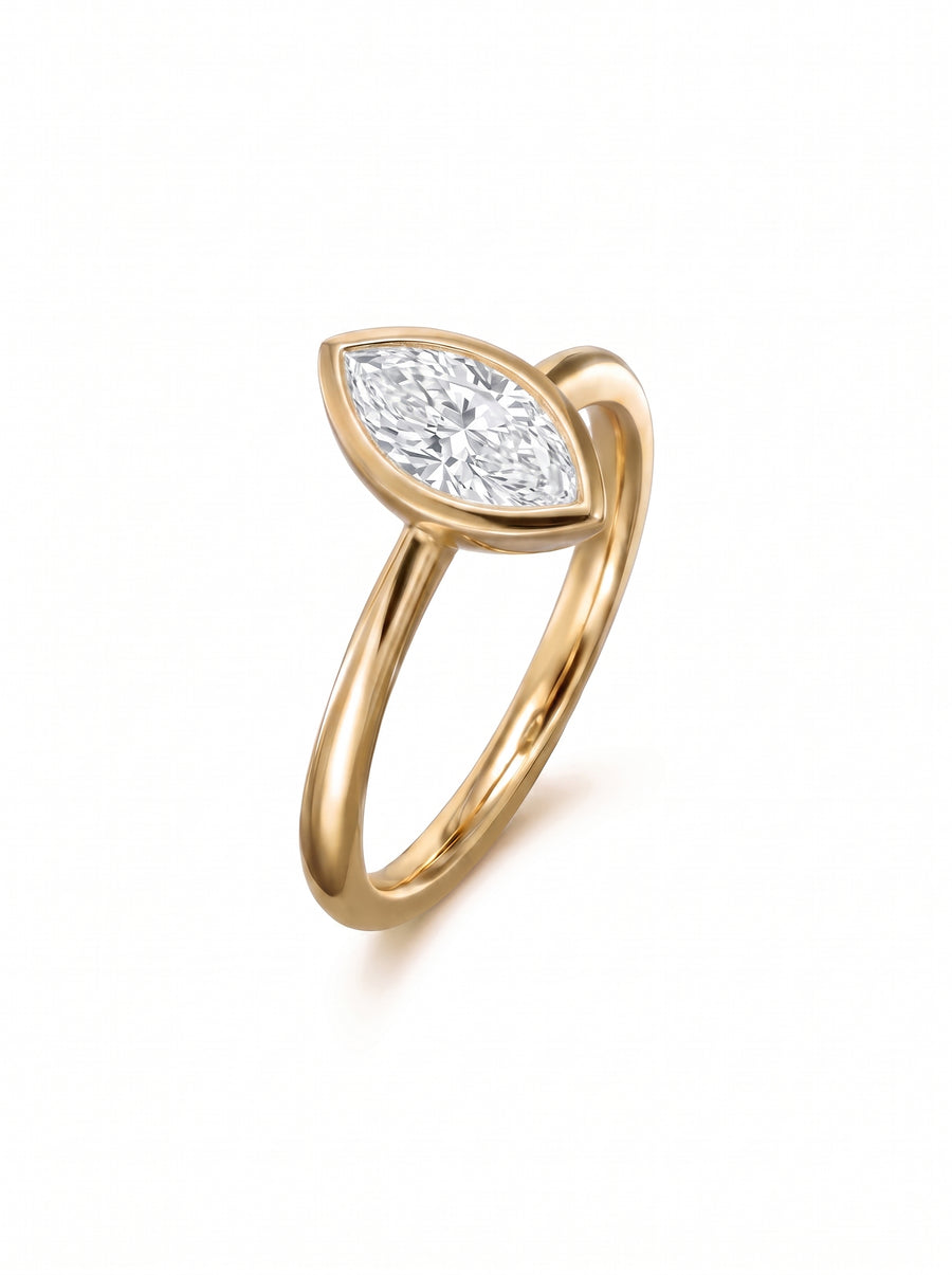 Marquise cut diamond engagement ring in a gold bezel setting on a white background.