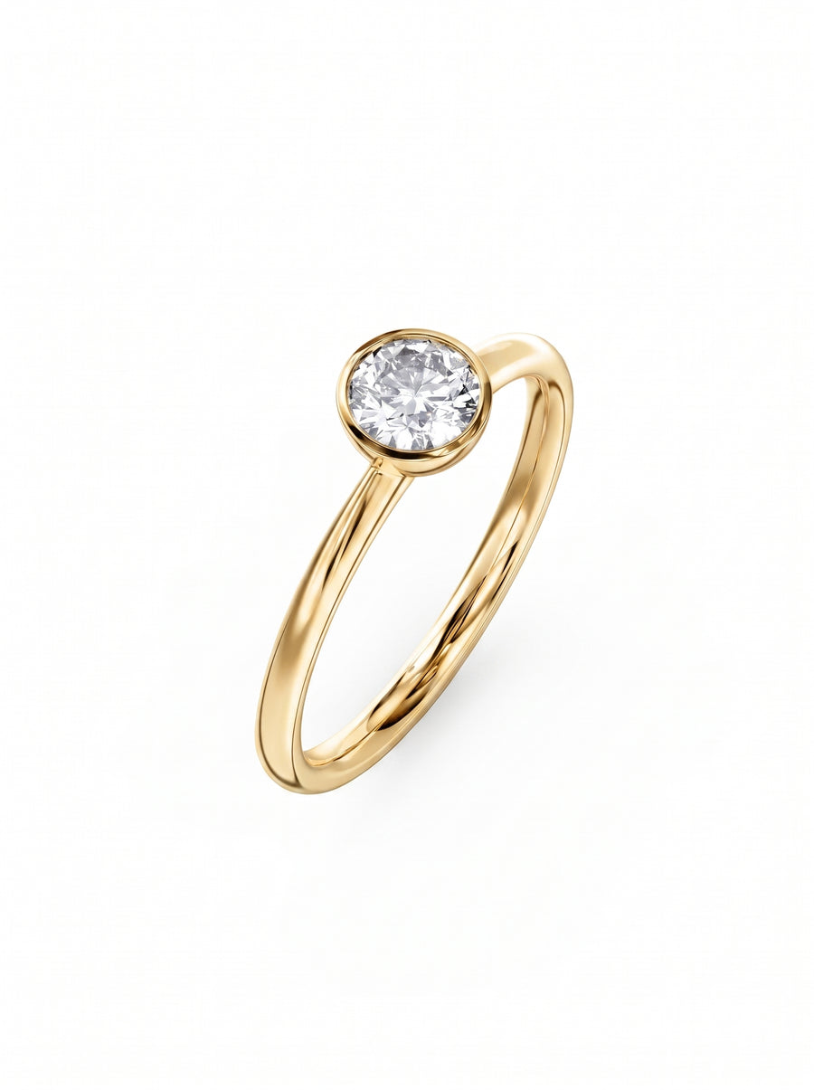 Round cut diamond engagement ring in a yellow gold bezel setting on a white background.