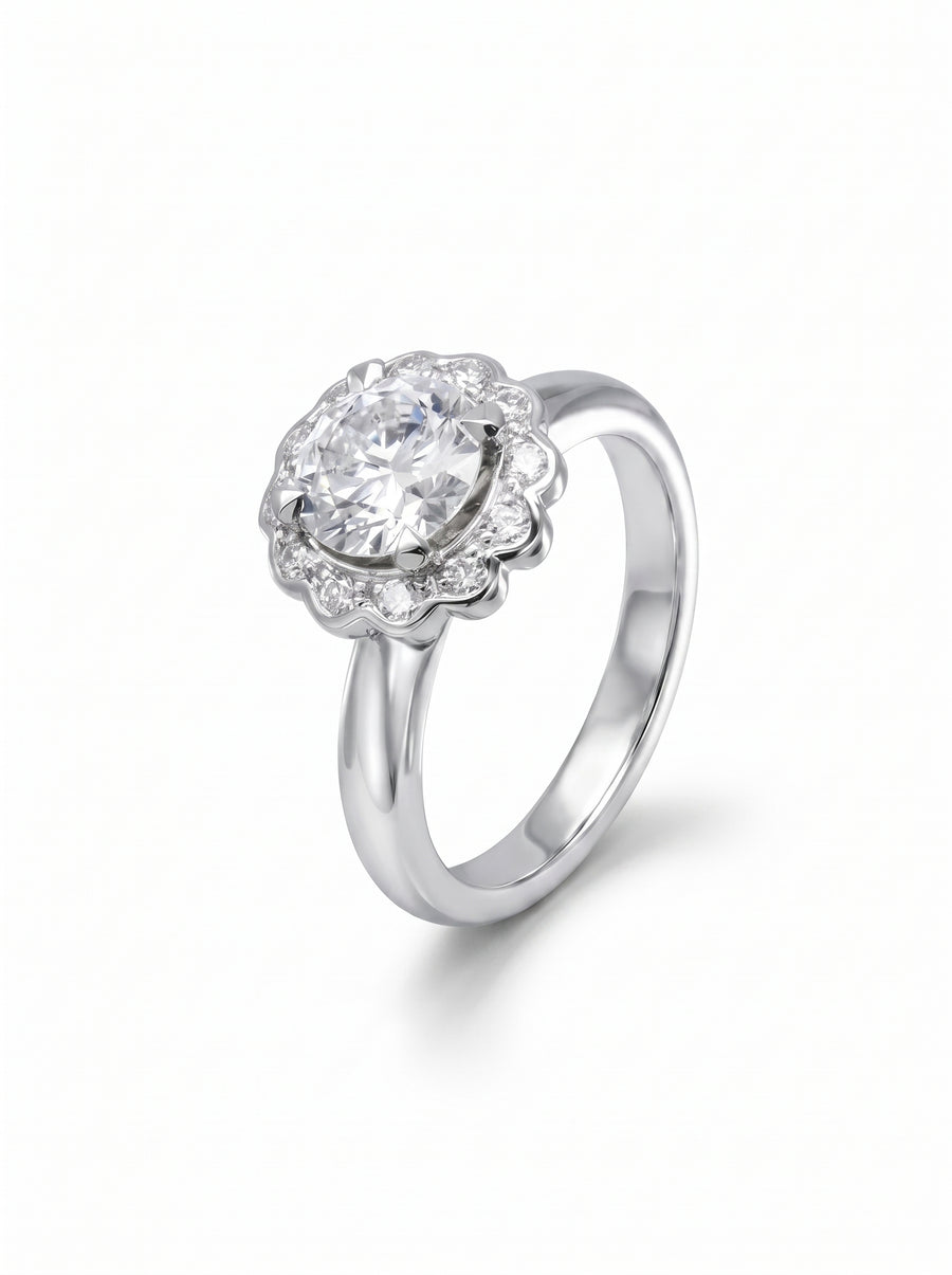 Silver engagement ring featuring a round diamond in a scalloped cluster setting with small accent stones.