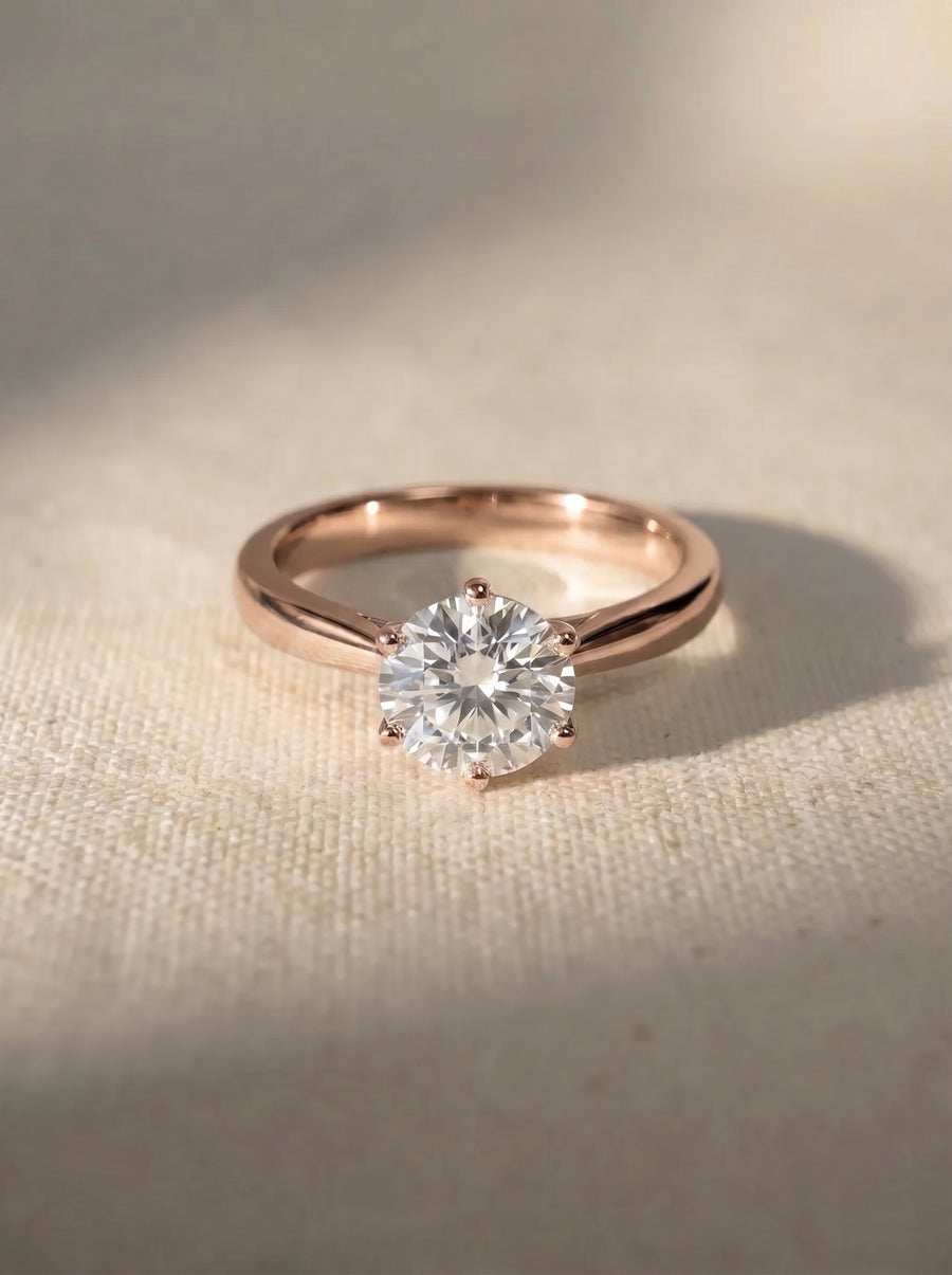 Rose gold engagement ring with a round brilliant cut diamond held by a six-claw setting.
