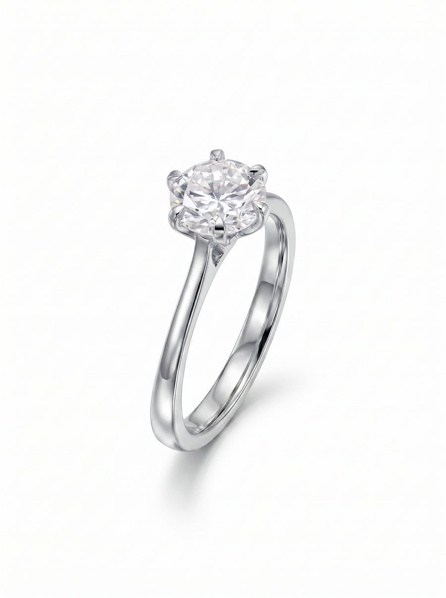Round cut solitaire diamond engagement ring set in a polished silver-tone metal band with six-prong talon setting.