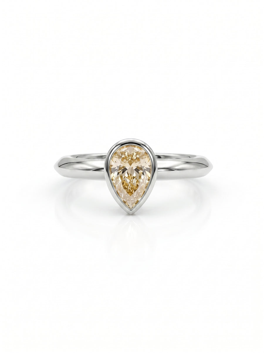 Pear cut champagne diamond solitaire ring in a silver-toned bezel setting on a plain band.