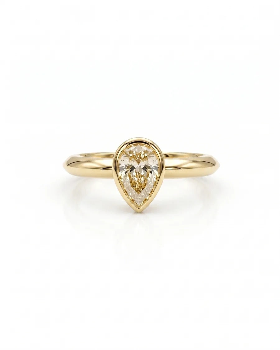 Pear cut diamond solitaire engagement ring in a yellow gold bezel setting on a plain band.