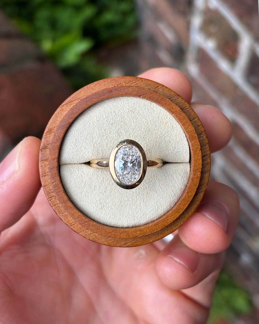 2.50ct oval cut lab-grown diamond engagement ring in a 9ct yellow gold bezel setting.