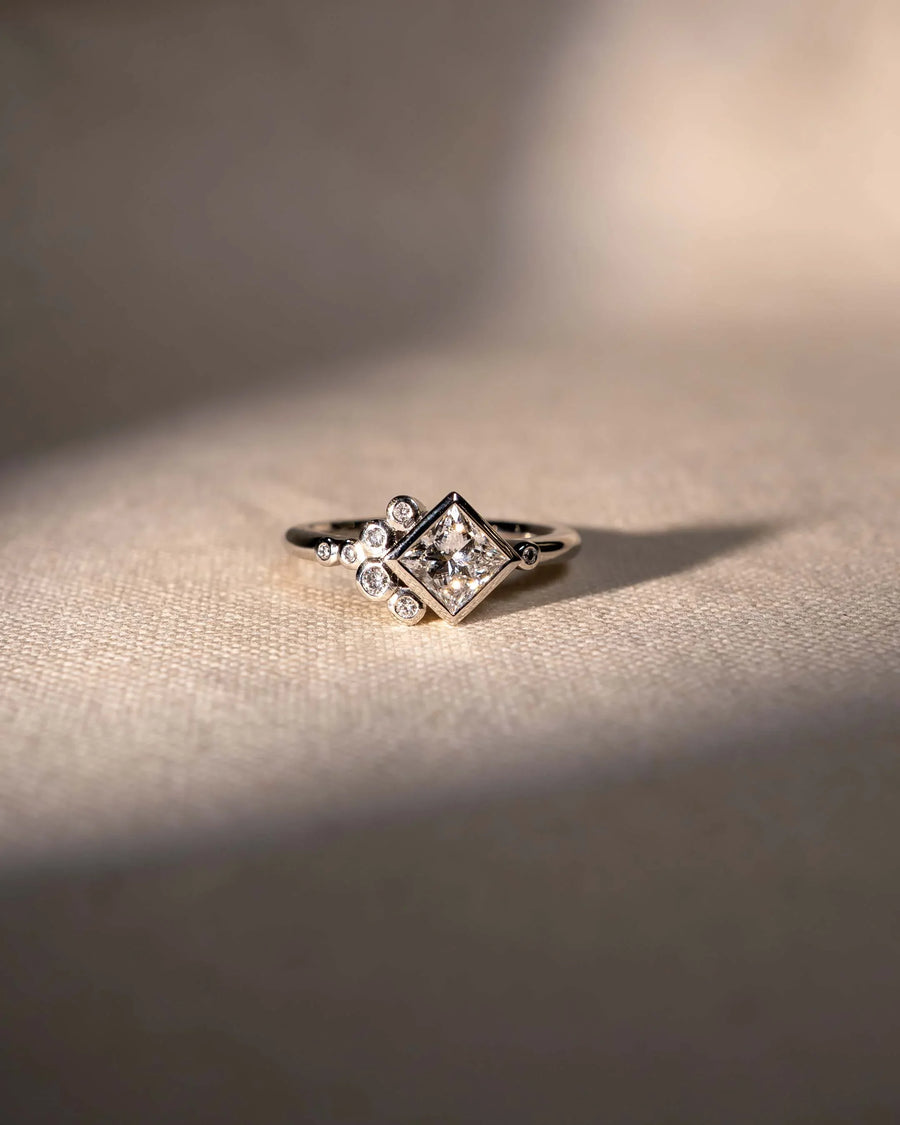 Platinum ring with a square lab-grown diamond and round accent diamonds.