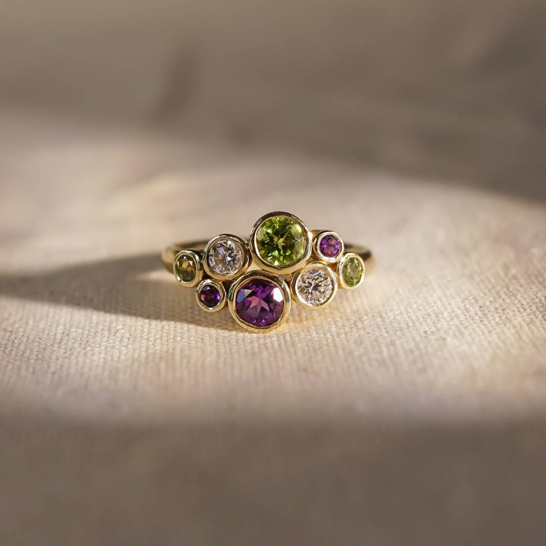 Gold ring with multicolored gemstones on a beige fabric background
