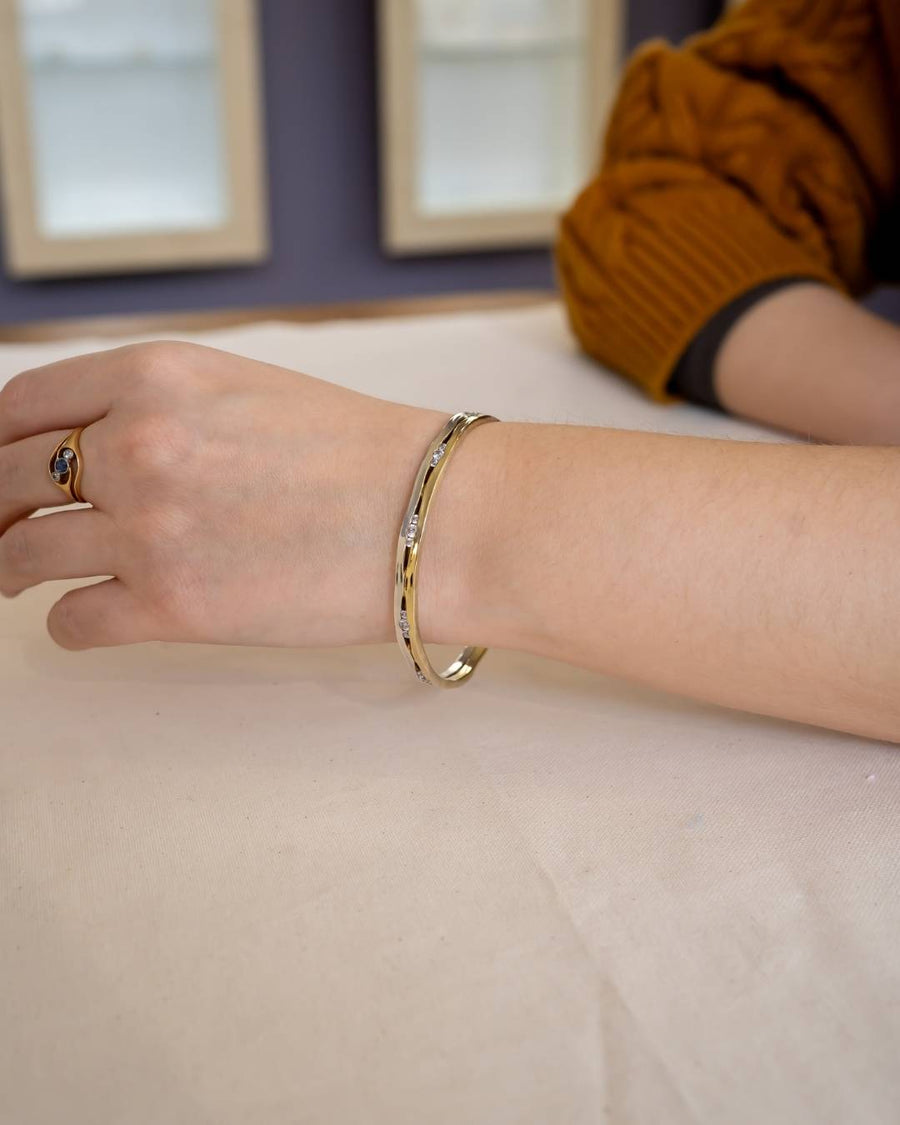 Hand wearing a gold bangle bracelet with diamonds, showcasing handmade luxury jewelry.