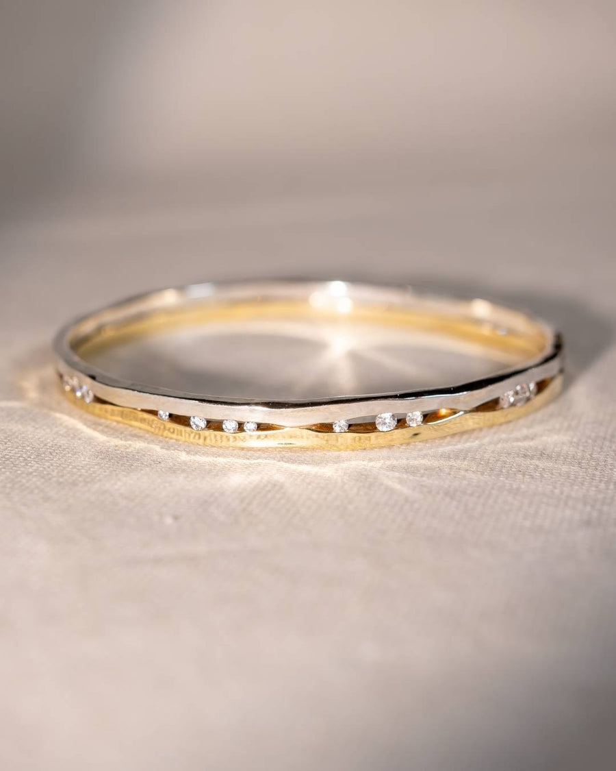 Gold and silver bangle with organic shape and scattered small diamonds on fabric