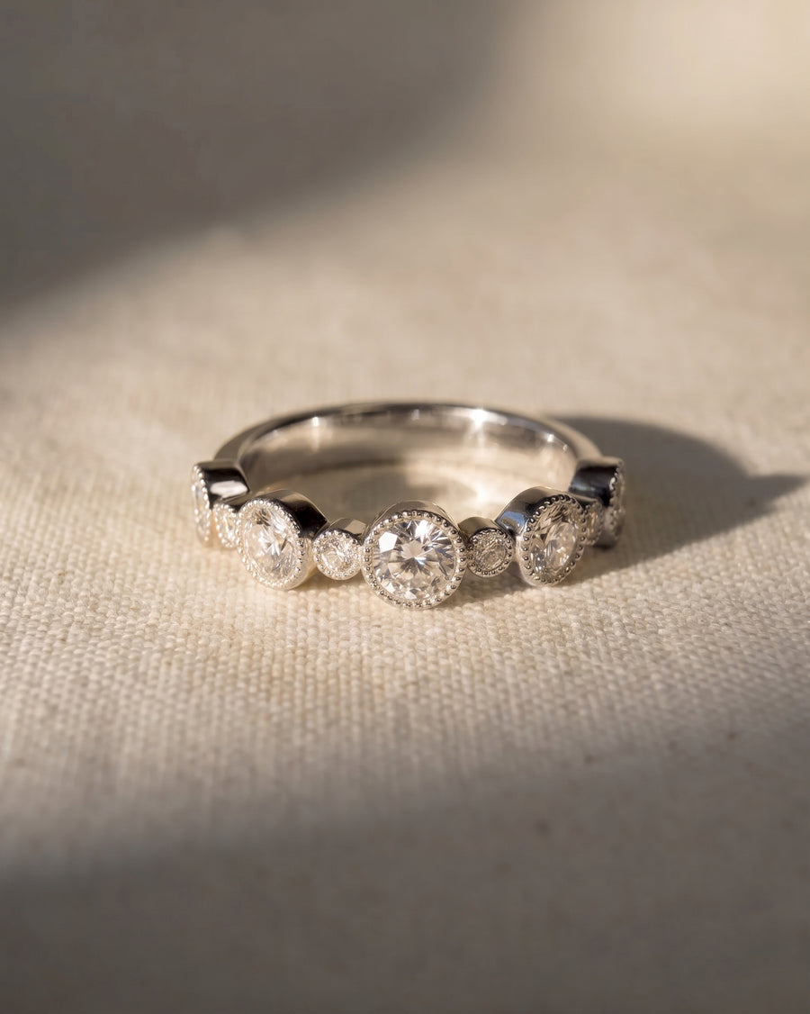 9ct white gold eternity ring with alternating round and smaller bezel-set diamonds.