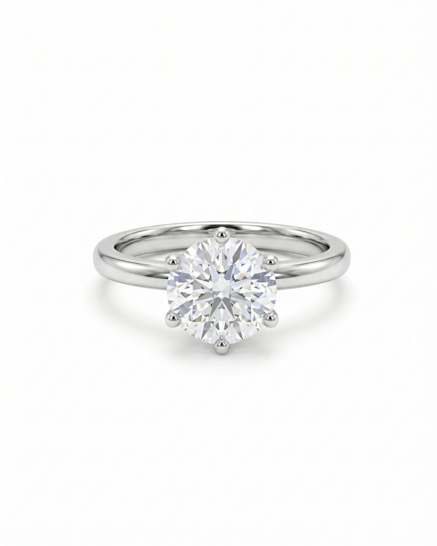 Round cut diamond solitaire engagement ring in a silver-toned metal band with a six-claw setting.