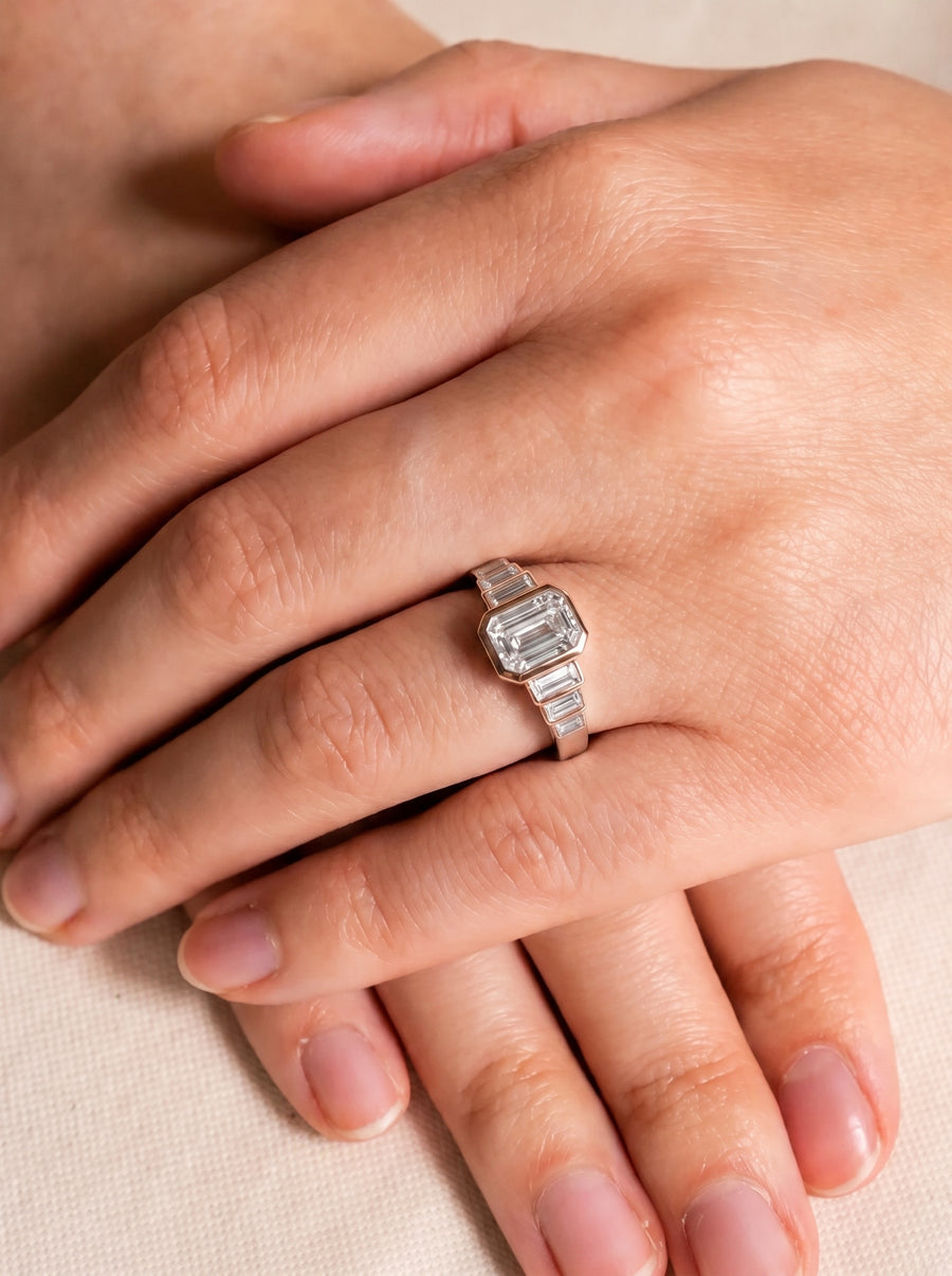Art deco engagement ring featuring an emerald cut diamond and baguette side stones in a platinum setting.