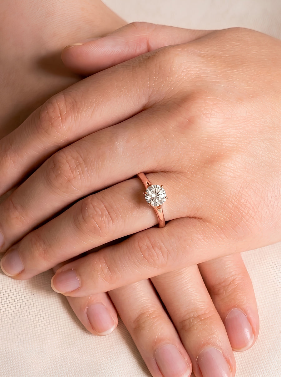 Round cut diamond engagement ring in rose gold with a tulip-style claw setting on a finger.