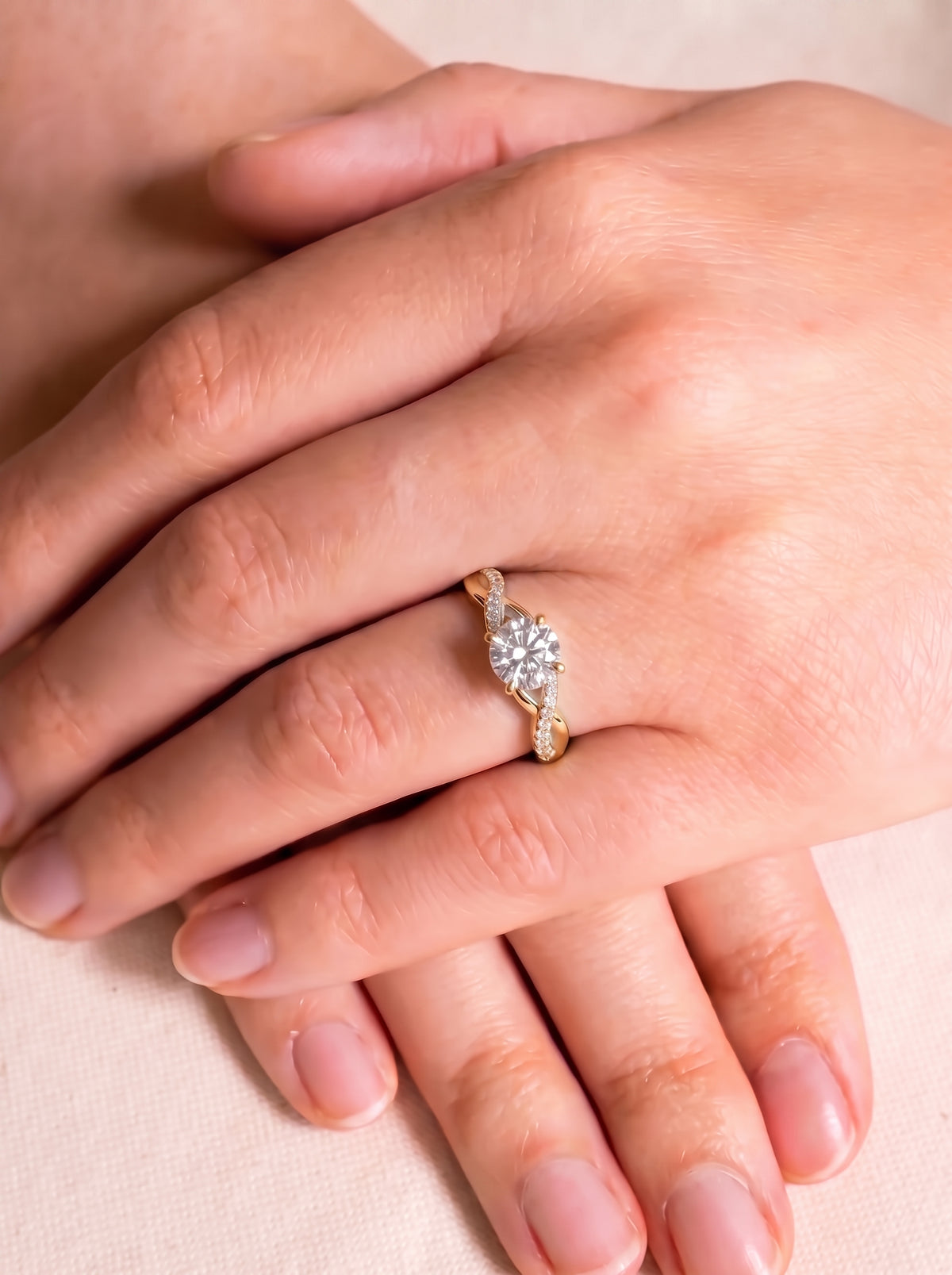 Round cut diamond engagement ring with a gold twist band and pavé accents on a person's finger.