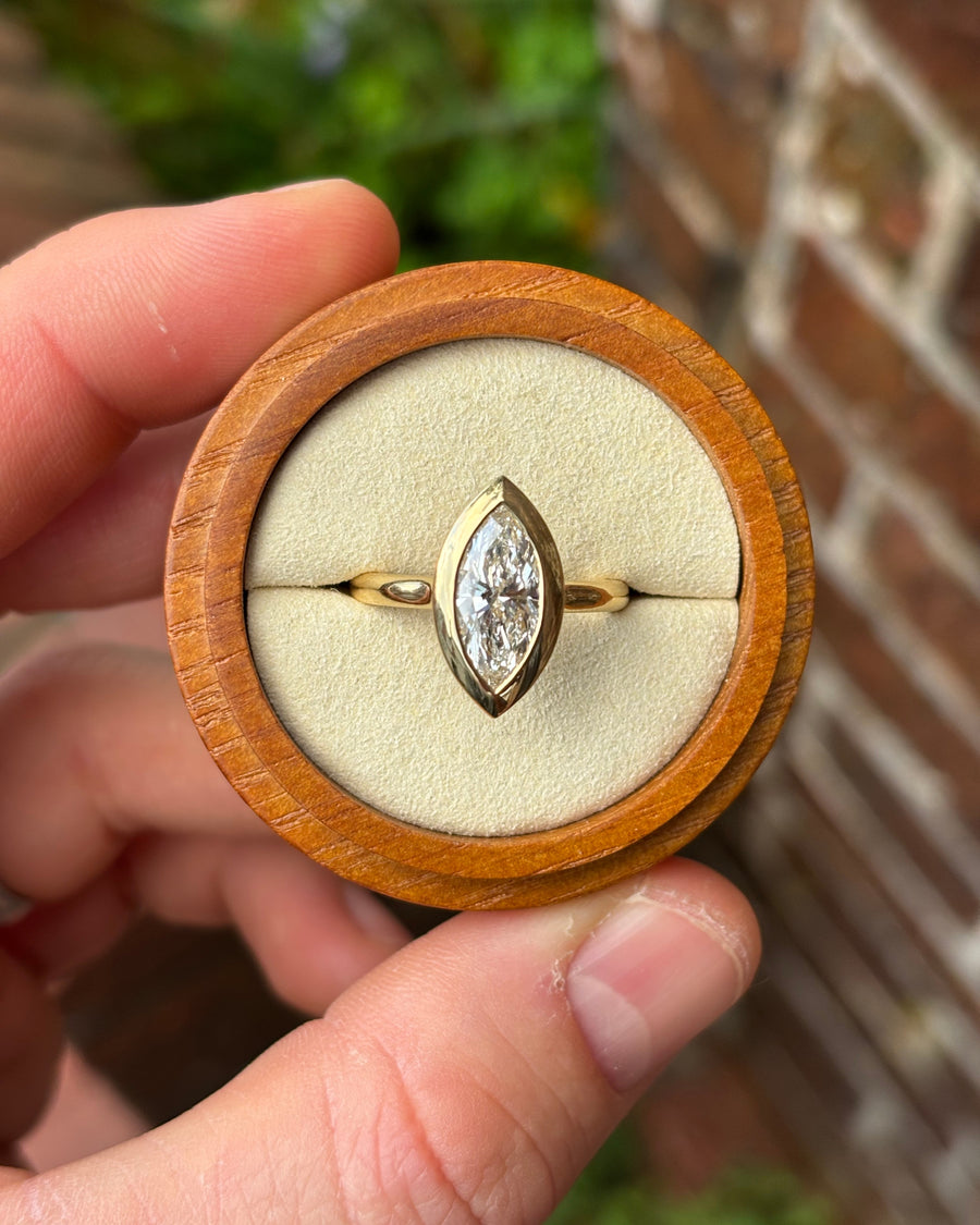 Marquise cut lab-grown diamond engagement ring in an 18ct yellow gold bezel setting inside a wooden box.