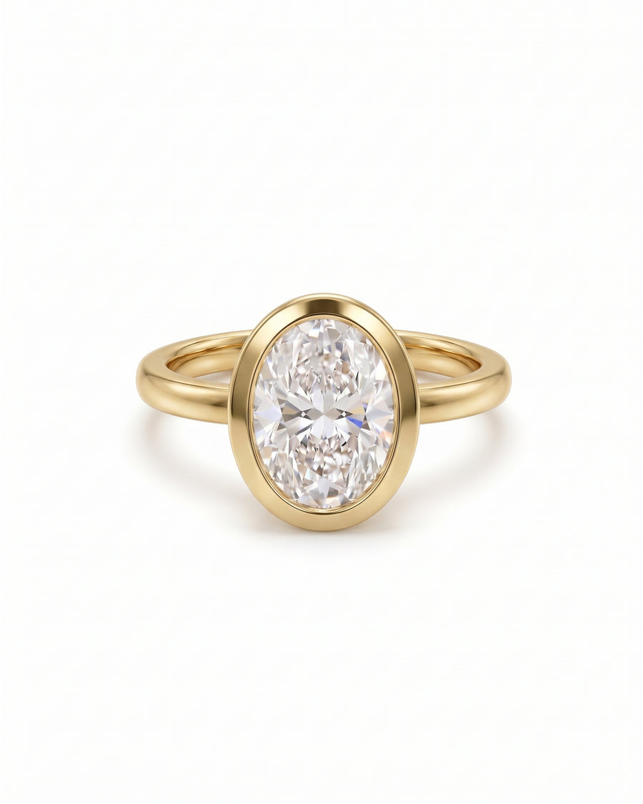 Oval cut lab-grown diamond engagement ring in a yellow gold bezel setting.