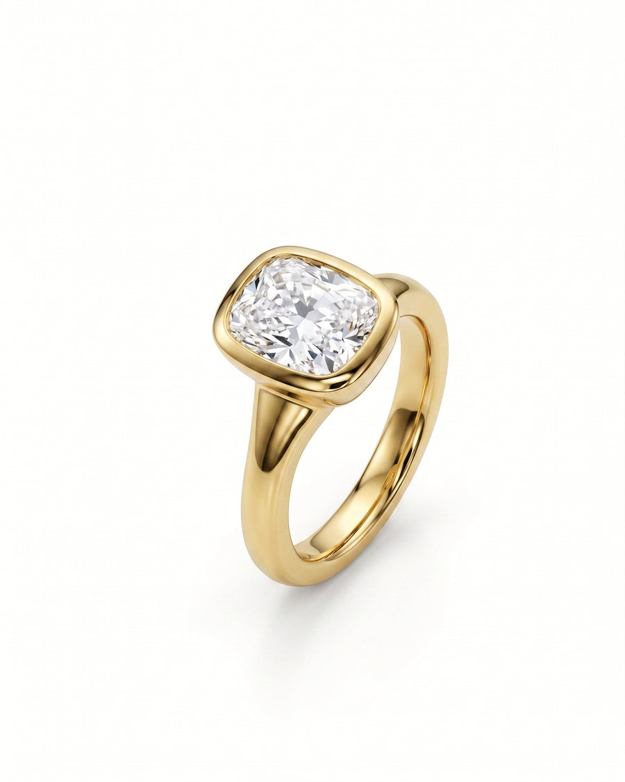 Gold ring with a chunky cushion cut diamond in a bezel setting.