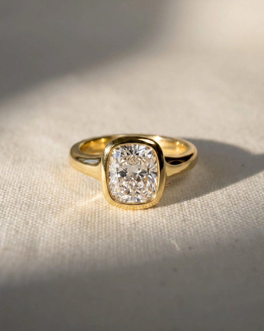 9ct yellow gold engagement ring with a chunky cushion cut diamond in a bezel setting.
