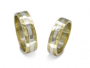 Wide flat wedding bands in yellow and white gold with a hammered texture finish.