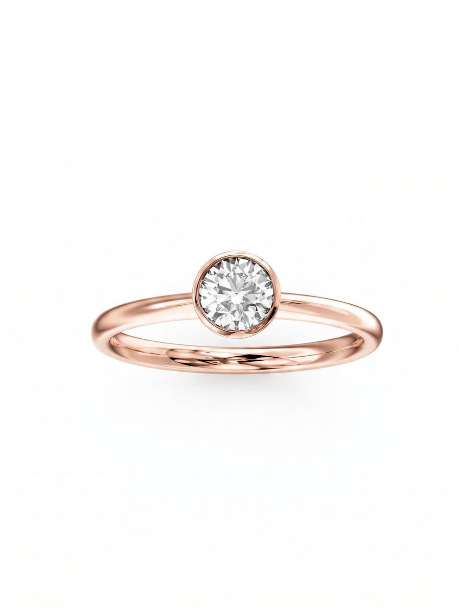 Round cut diamond engagement ring in a rose gold bezel setting on a white background.