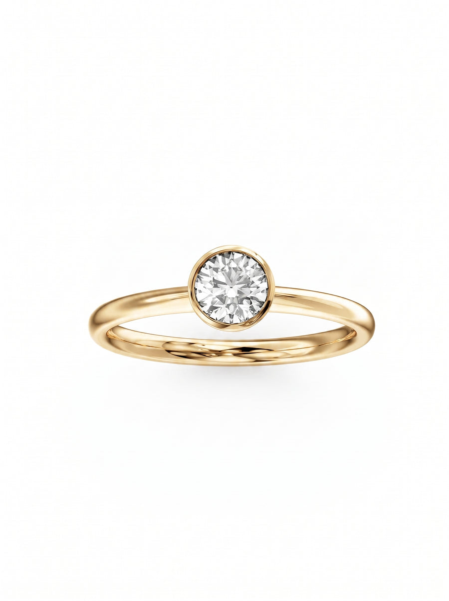 Round brilliant cut diamond solitaire ring in a yellow gold bezel setting on a plain band.