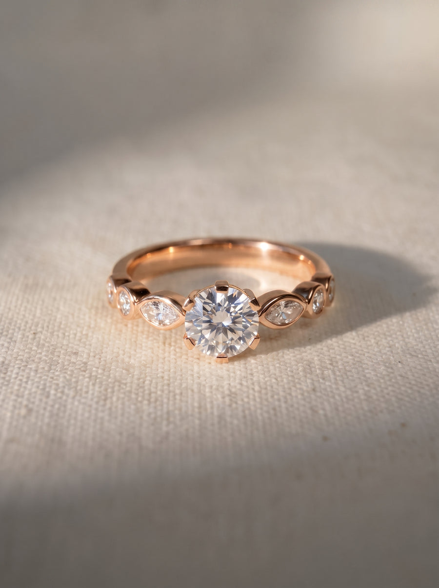 Rose gold engagement ring featuring a round cut center stone and marquise cut side diamonds.