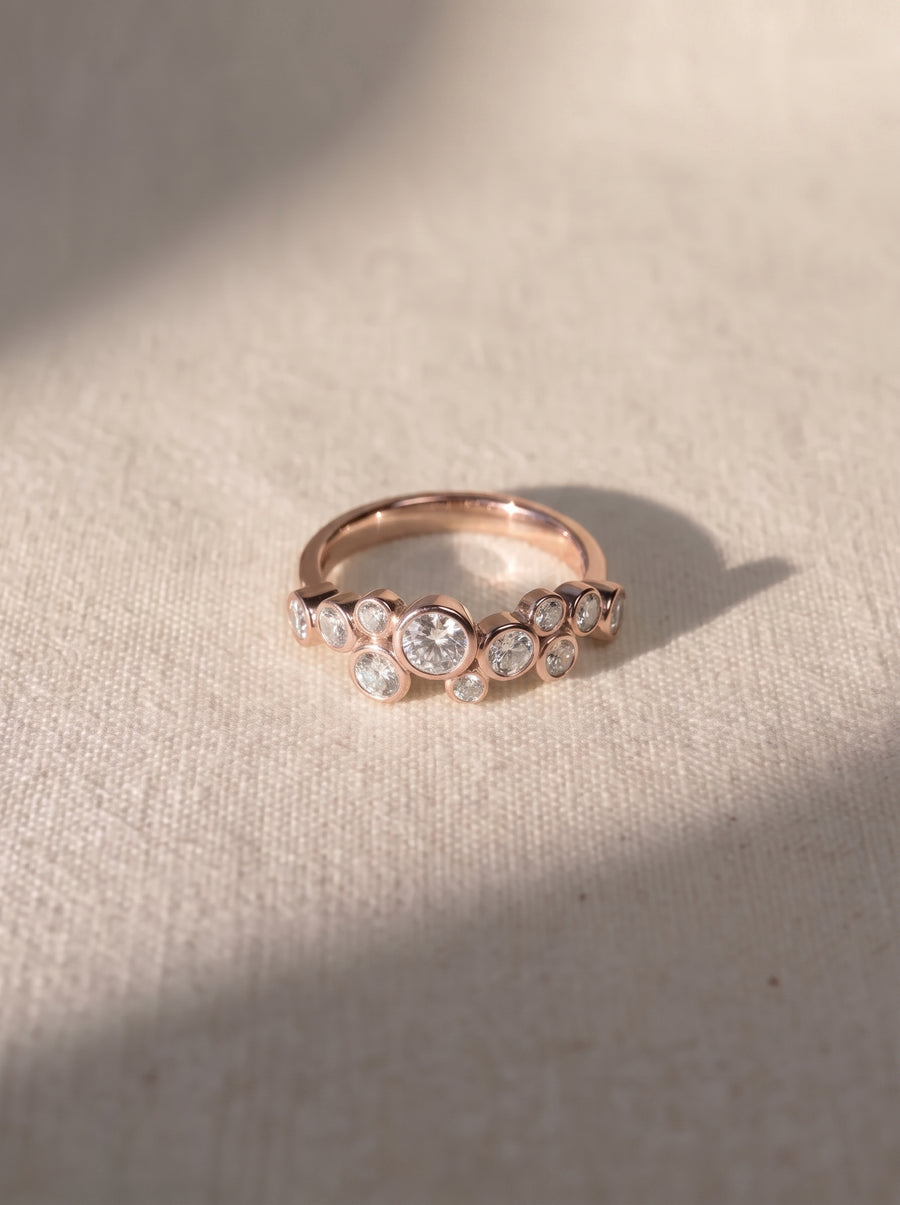 Rose gold engagement ring featuring multiple bezel-set round cut diamonds in a cluster bubble design.