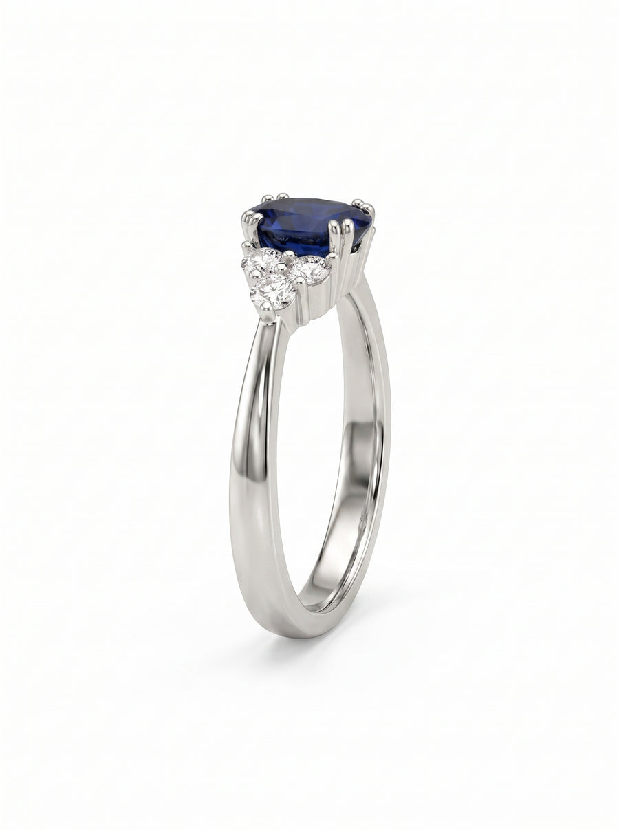 Platinum engagement ring with a blue sapphire center stone and three small diamonds on each side.