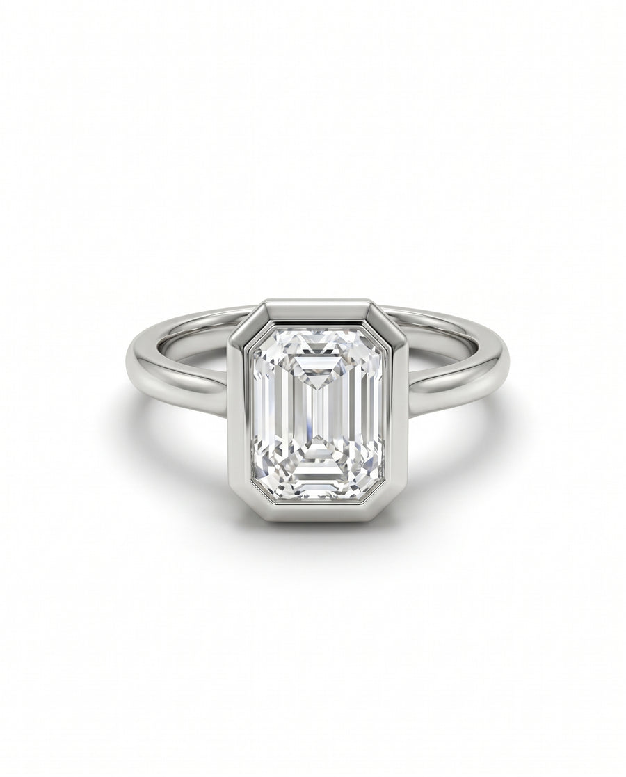 Emerald cut lab-grown diamond engagement ring in a platinum bezel setting on a plain band.