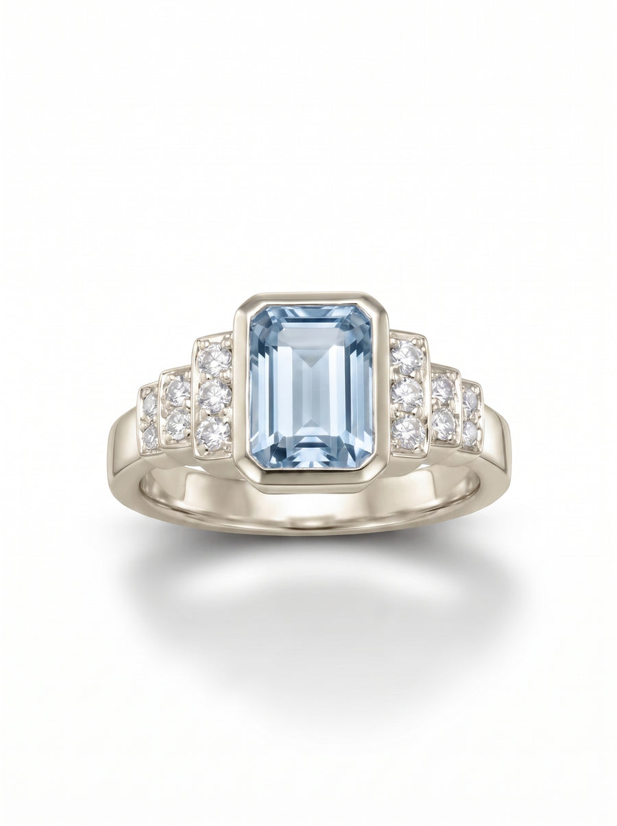Art deco engagement ring featuring an emerald-cut aquamarine and round diamonds set in white gold.