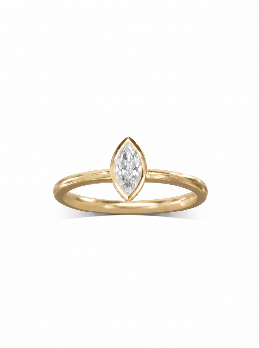 Marquise cut diamond engagement ring in a yellow gold bezel setting on a white background.