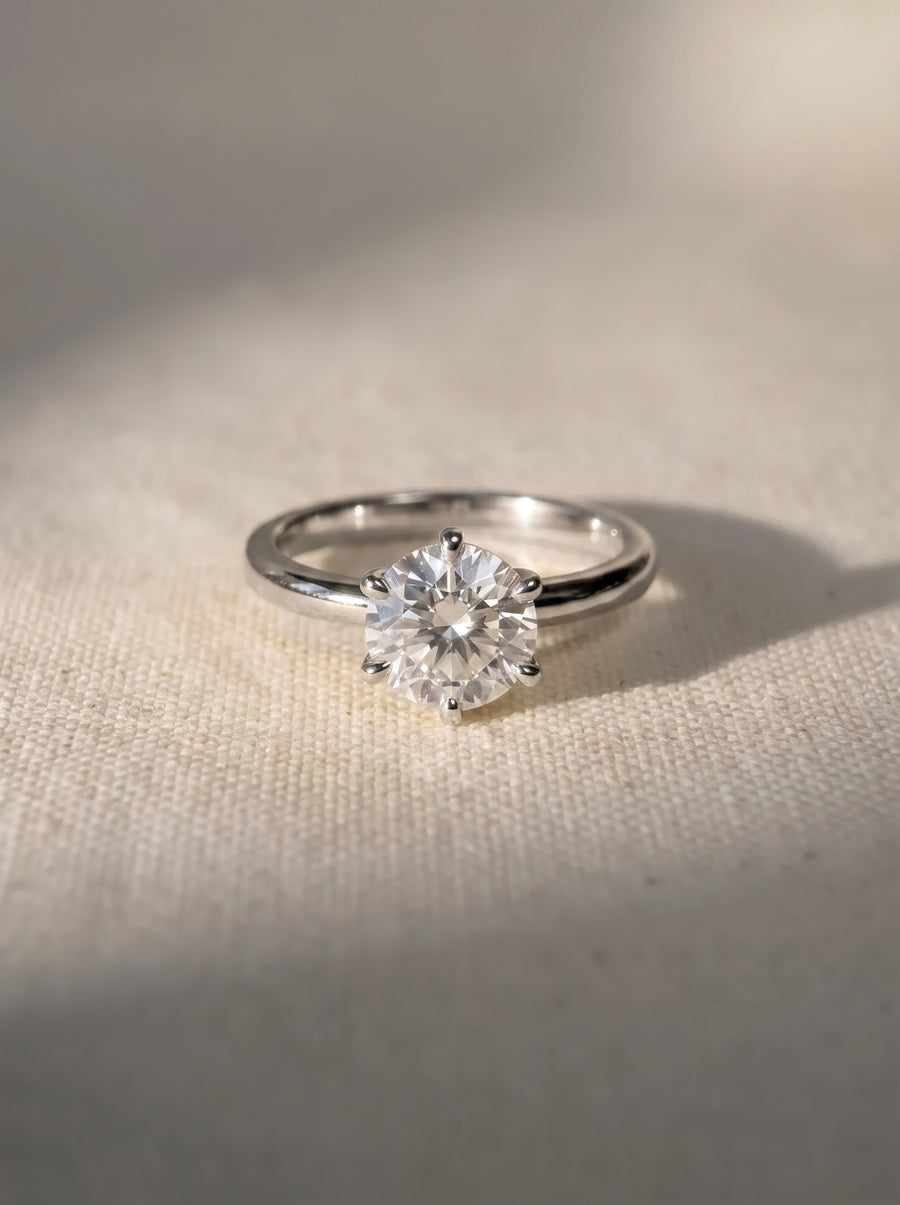 Round cut solitaire diamond engagement ring with a six-prong setting on a silver band.
