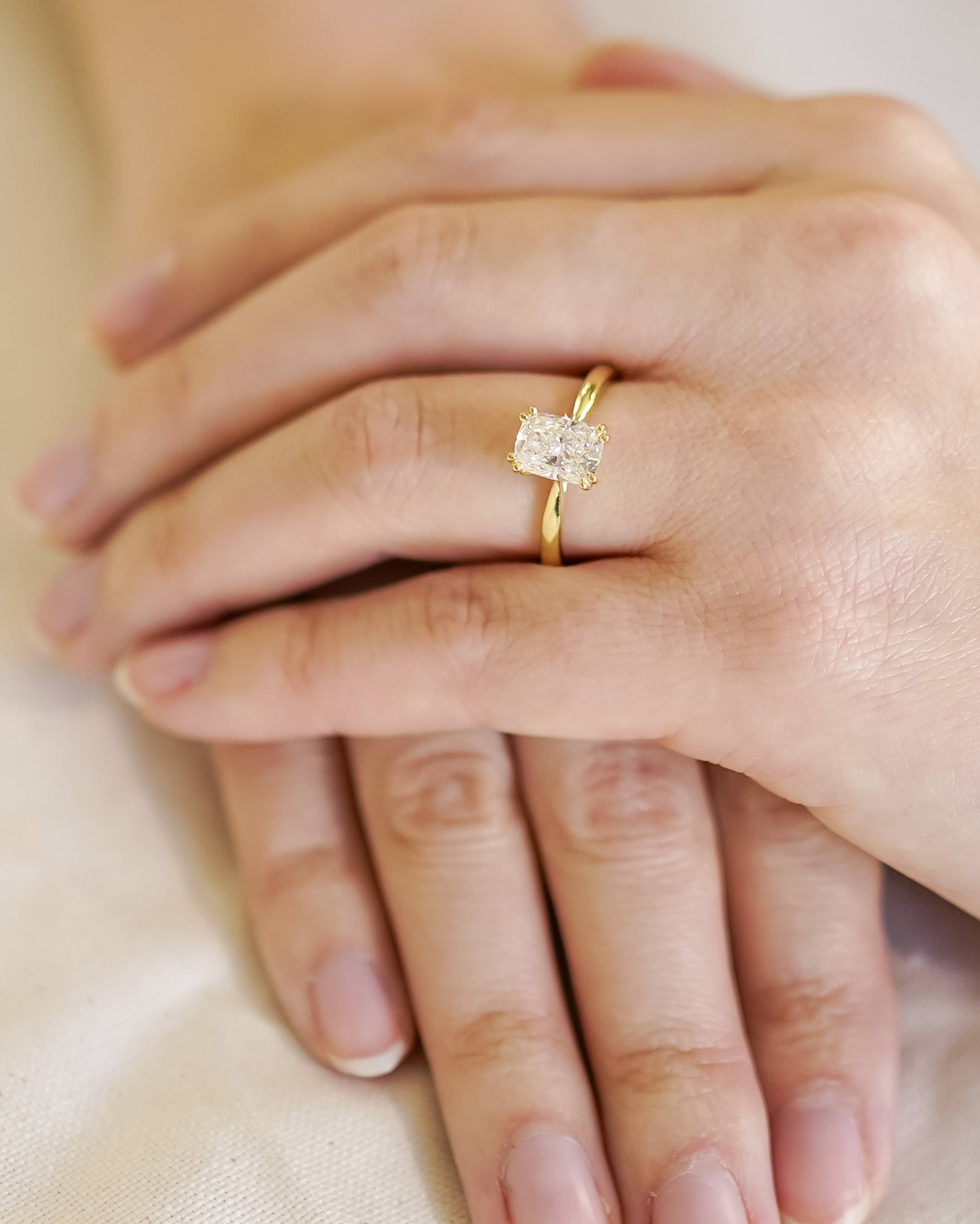 Gold ring with a diamond on a hand against a neutral background